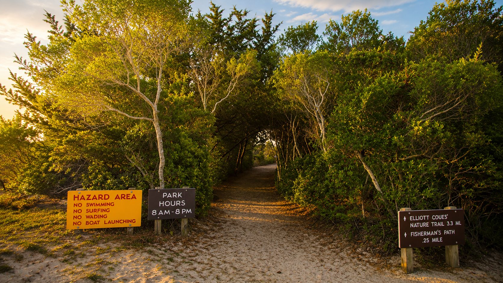 The Elliott Coues Nature Trail entrance at Fort Macon, framed by a canopy of trees
