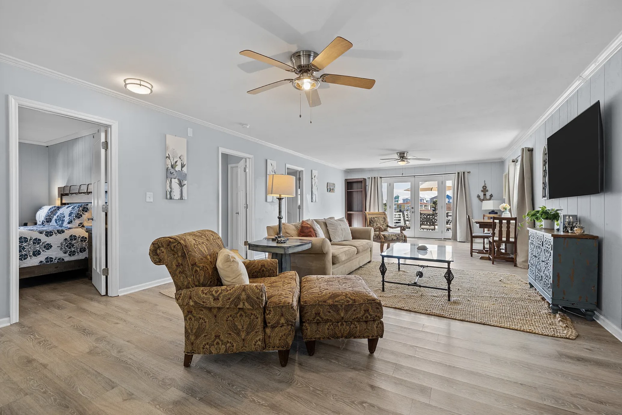 Living room seating with armchair and ottoman, bedroom visible through open door