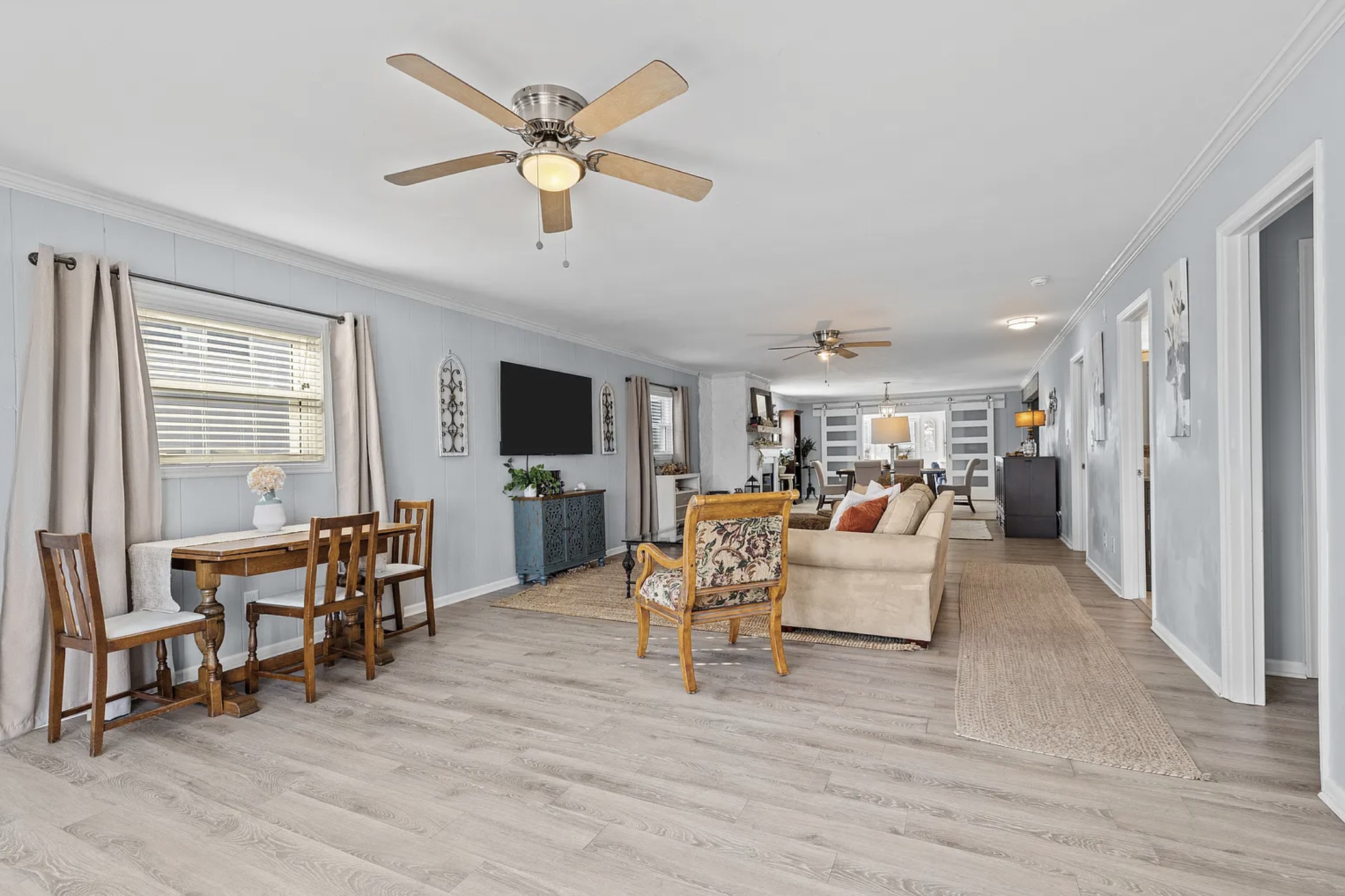 Living room with wood dining table, teal cabinet, and sofa seating