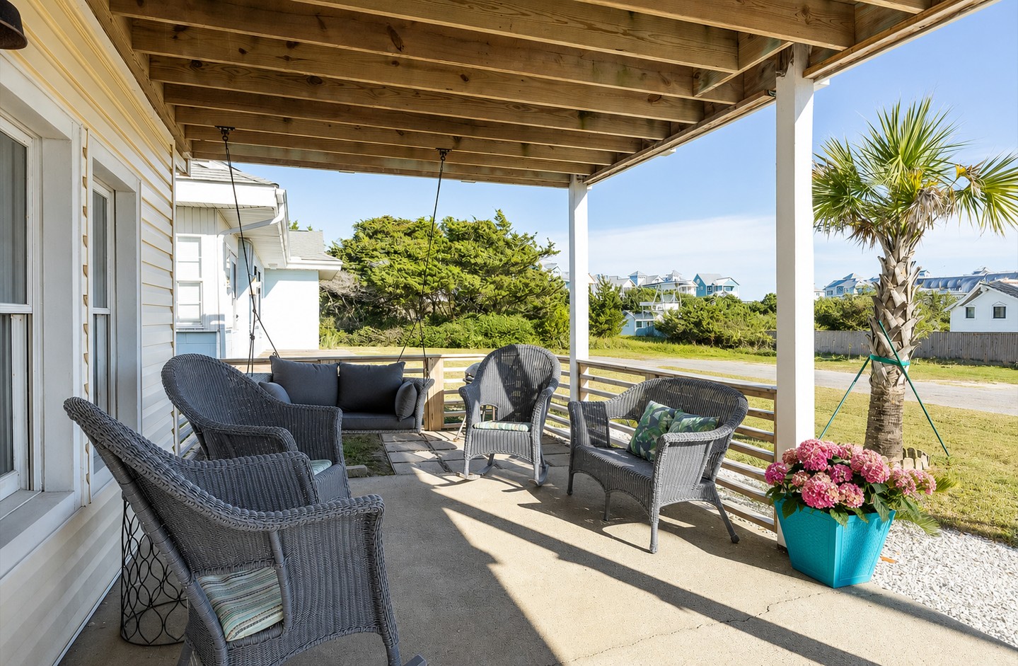 Porch with gray wicker rockers, swing, and view of the yard